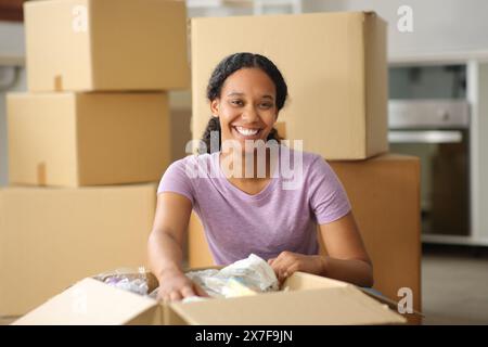 Glückliche schwarze Frau zieht aus dem Haus und sieht dich an, wie du eine Kiste öffnest Stockfoto