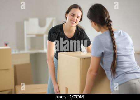 Zwei Frauen leiden daran, schwere Kisten zu heben, die nach Hause ziehen Stockfoto