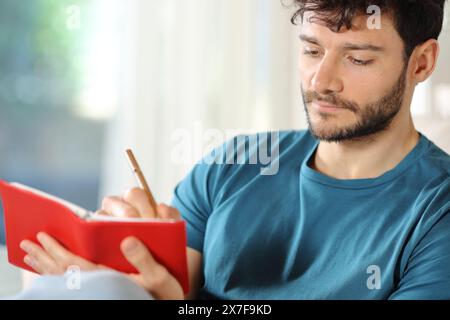 Ein ernster Mann, der zu Hause auf der roten Agenda sitzt Stockfoto