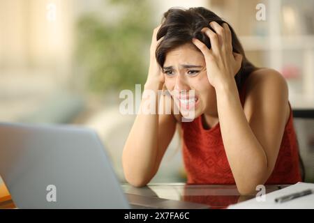 Ein verzweifelter Student beschwert sich, der zu Hause den Laptop überprüft Stockfoto