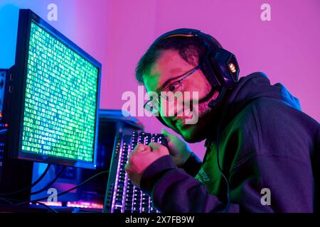 Ein lächelnder, glücklicher Mann hackt sich in die Konten von Menschen und Unternehmen ein und holt sich ihre Informationen Stockfoto