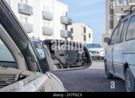 Ein kaputter Spiegel an einem verlassenen Auto spiegelt den Schaden und die Vernachlässigung wider, die es im Laufe der Zeit erlitten hat. Stockfoto