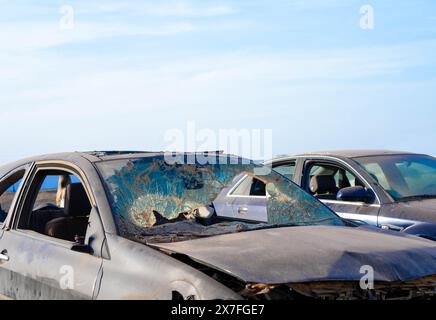Zwei Autos, die nach einer Kollision verlassen wurden, werden durch gebeulte Rahmen und zersplitterte Fenster schwer beschädigt. Stockfoto