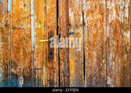Alte, abgenutzte hölzerne Eingangstür mit abblätternder Farbe als Grunge-Textur und Hintergrund Stockfoto