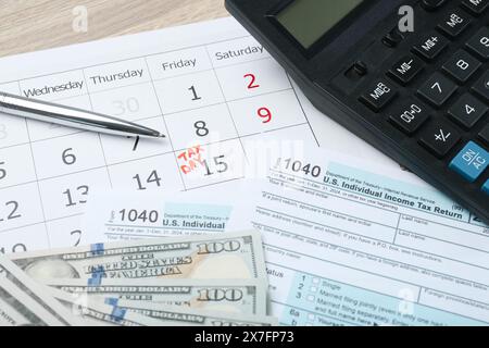 Steuertag. Kalender mit Datumserinnerung, Dokumenten, Dollarscheine, Stift und Taschenrechner auf dem Tisch Stockfoto