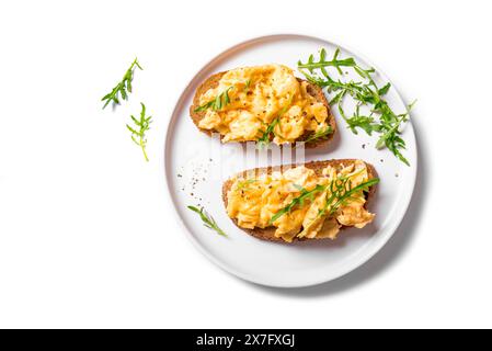 Rührei-Sandwiches auf weißem Teller isoliert auf weißem Hintergrund, gesundes Keto-Frühstück. Vollkorntoast mit Rührei und Bio-Rucolu Stockfoto