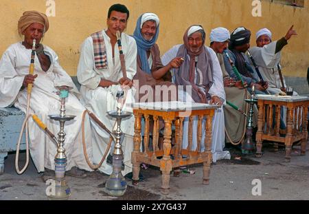 Ägyptische Männer genießen lebhafte Gespräche und traditionelle Hookahs auf einem Luxor Straßenmarkt. Stockfoto