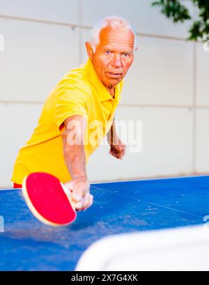 Reifer Mann, der draußen Tischtennis spielt Stockfoto