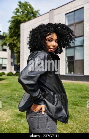 Eine stilvolle, vielseitige Frau steht selbstbewusst vor einem modernen Gebäude. Stockfoto