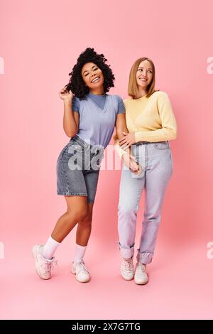 Zwei verschiedene Frauen in lässiger Kleidung stehen vor einem leuchtend rosa Hintergrund zusammen. Stockfoto