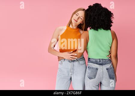 Zwei verschiedene Damen in kuscheliger Freizeitkleidung stehen vor einem leuchtend rosa Hintergrund. Stockfoto