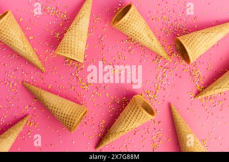 Eiswaffelkegel und bunte Streusel auf rosafarbenem Hintergrund. Süßes, sommerliches und leeres Konzept. Draufsicht. Flache Lagen Stockfoto