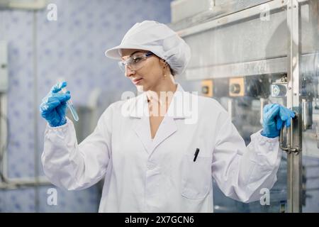 Produktqualitätskontrolle weibliche Beamtin, die in der Trinkwasserfabrik arbeitet, um die Sauberkeit, Nährstoff- und Chemikalienstandards zu überprüfen Stockfoto