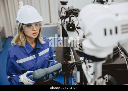 Ingenieurinnen, Universitätsstudentin, lernen, wie man den Industrieroboterarm mit Fernbedienung bedient, im Laborklassenzimmer von Robotikingenieuren in Polytechn Stockfoto