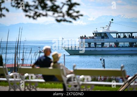 20. Mai 2024, Baden-Württemberg, Überlingen am Bodensee: Das Passagierschiff Seegold fährt auf dem Bodensee zur Anlegestelle, während ein Paar auf einer Bank im Uferpark im Vordergrund sitzt. Foto: Felix Kästle/dpa Stockfoto