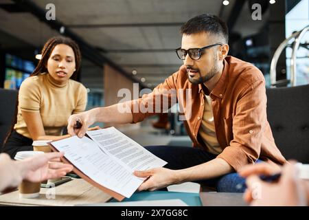 Eine vielfältige Gruppe von Kollegen versammelt sich an einem Tisch, diskutiert Papiere und erarbeitet Ideen für ihr Startup-Team. Stockfoto