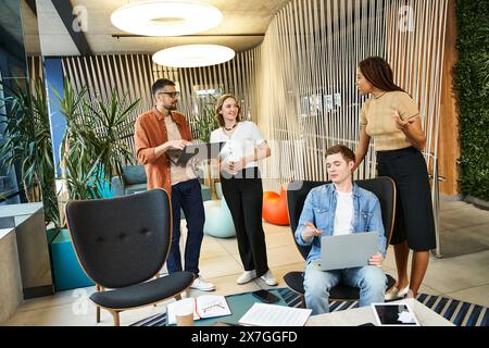 Eine Gruppe von Kollegen in einem modernen Coworking-Bereich, die sich mit Laptops um einen Tisch gedrängt haben und an einem Startup-Projekt mitarbeiten. Stockfoto