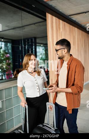 Ein Mann und eine Frau stehen in einer Hotellobby mit einem Koffer und bereiten sich auf eine Geschäftsreise vor. Stockfoto