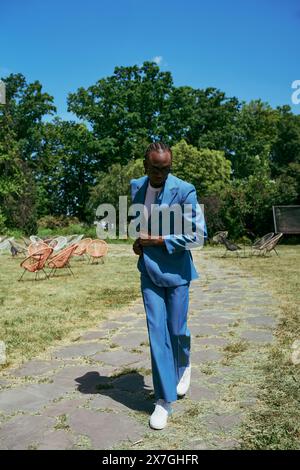 Ein kultivierter Afroamerikaner in einem blauen Anzug spaziert durch lebhaftes Grün. Stockfoto