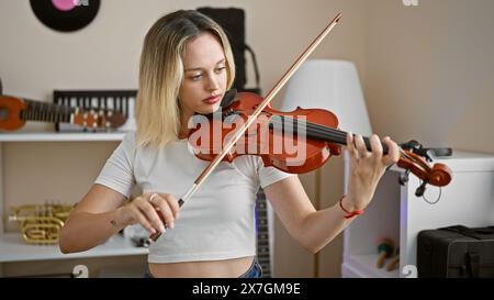 Junge blonde Musikerin, die im Musikstudio Violine spielt Stockfoto