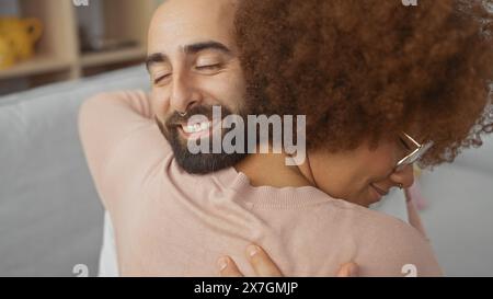 Nahaufnahme eines glücklichen interrassischen Paares, das sich in einer gemütlichen Innenumgebung umschließt und Liebe und Zufriedenheit widerspiegelt. Stockfoto