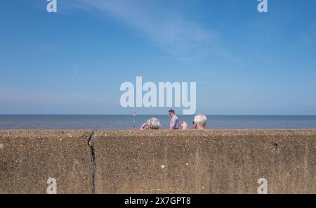 Zwei ältere Ehepaare, die auf das Meer zeigen und vor einer Betonmauer im Badeort Hunstanton, Norfolk, sitzen. Stockfoto