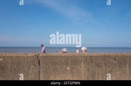 Zwei ältere Ehepaare, die auf das Meer zeigen und vor einer Betonmauer im Badeort Hunstanton, Norfolk, sitzen. Stockfoto