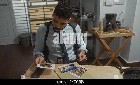 Hispanic Detective analysiert Beweise in einem Polizeirevier und zeigt einen Mann in Nachsicht. Stockfoto