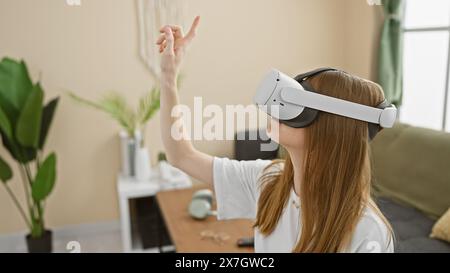 Eine junge Frau verwendet ein Virtual-Reality-Headset in einem modernen Wohnzimmer und interagiert mit Technik. Stockfoto
