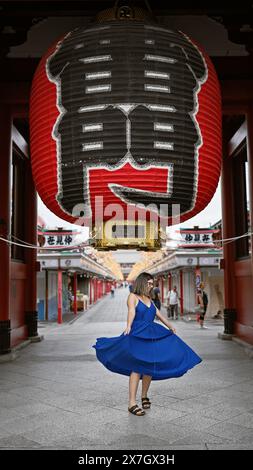 Die sprudelnde hispanische Frau tanzt fröhlich und dreht sich in wunderschönem Kleid inmitten der herrlichen Architektur des Senso-JI-Tempels in tokio. Sie ist durch japan gereist Stockfoto