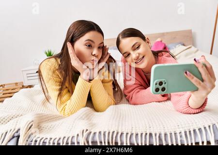 Zwei hübsche Teenager-Mädchen in lässiger Kleidung liegen auf einem Bett und machen Selfie Stockfoto