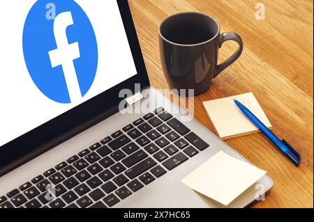 20. Mai 2024: Laptop auf dem Schreibtisch mit dem Facebook-Logo auf dem Bildschirm. FOTOMONTAGE *** Laptop Computer auf Schreibtisch mit dem Facebook Logo auf dem Bildschirm. FOTOMONTAGE Stockfoto