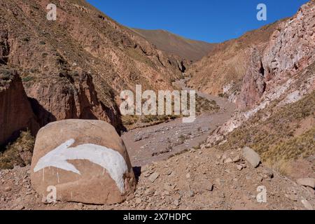 Felsen mit einem Pfeil darauf, um die Richtung in die Berge in Iruya, Argentinien, zu zeigen. Stockfoto