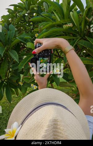 Das Mädchen mit dem Hut fotografiert Blumen auf der Kamera im Urlaub Stockfoto