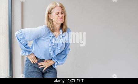 Eine blonde Frau leidet, weil sie Blinddarmschmerzen hat. Stockfoto