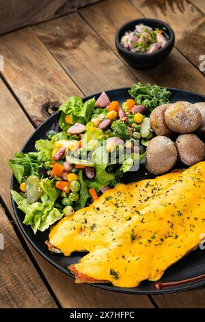 Gebratene Forelle in Zwiebelsauce mit Salat und gebackenen Kartoffeln gebadet Stockfoto