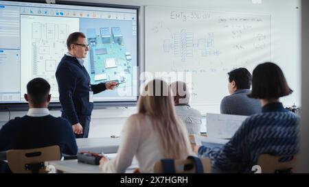 Selbstbewusster männlicher Lehrer mit interaktivem Digital Screen, spricht mit einer Gruppe verschiedener Studenten aus dem Maschinenbau und zeigt das 3D-Modell der Leiterplatte. Bildung und High-Tech-Konzept. Stockfoto