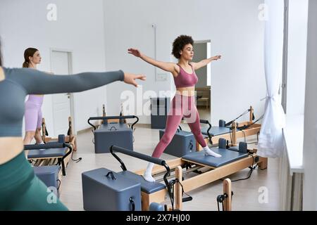 Eine Gruppe hübscher, sportlicher Frauen, die während eines Pilates-Kurses im Fitnessstudio Übungen machen. Stockfoto