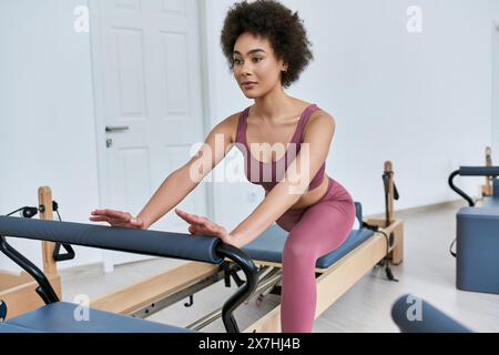Frau in rosa Oberteil und Leggings, die anmutig trainiert. Stockfoto