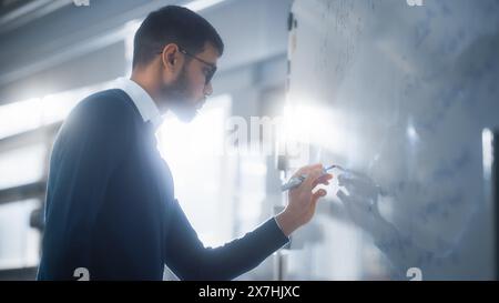 Schwarzer Wissenschaftler löst komplexe mathematische Probleme und schreibt lange Formeln auf Whiteboard. Hochschulbildung, Wissenschaft, Technologie und Innovationskonzept. Stockfoto