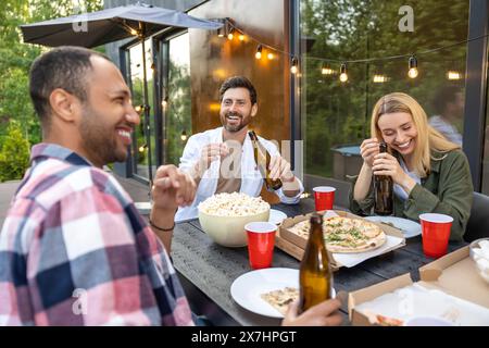 Fröhliche Freunde, die Spaß beim Toasten von Biergläsern im Freien haben, um eine angenehme Veranstaltung zu feiern Stockfoto