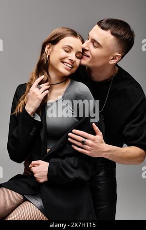 Ein junges verliebtes Paar posiert in einem Studio mit grauem Hintergrund, das Anmut und Harmonie ausstrahlt. Stockfoto