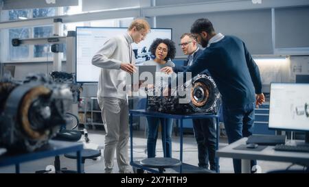 Verschiedene Ingenieure arbeiten gemeinsam an der Funktionsänderung von Elektromotoren für ein innovatives Projekt. Ingenieurwesen und nachhaltige Energietechnologien für moderne Fahrzeuge. Stockfoto