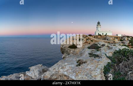 Ein Blick auf den Leuchtturm Cap de Cavalleria auf Menorca bei Sonnenuntergang mit Vollmond Stockfoto