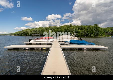 Die Sonne scheint auf einem ruhigen Dock, während die Boote im rauschenden Wasser des Deep Creek Lake im ländlichen Garrett County, Maryland, USA, schweigen. Stockfoto