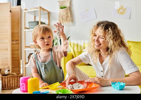 Eine lockige Mutter und ihre Kleinkind-Tochter nahmen an einer Montessori-Erziehung an einem Tisch Teil. Stockfoto