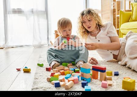 Eine lockige Mutter und ihre Tochter spielen Montessori und bauen zusammen mit farbenfrohen Blöcken auf dem Boden. Stockfoto