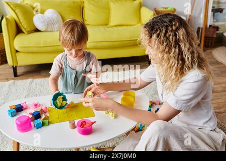 Eine lockige Mutter spielt mit ihrer Kleinkind-Tochter in Montessori und erforscht gemeinsam Spielzeug in einer warmen Atmosphäre. Stockfoto