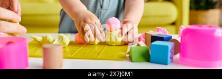 Das Kind spielt gerne mit verschiedenen Spielzeugen und spielt fantasievolle Aktivitäten auf einem Tisch zu Hause. Stockfoto