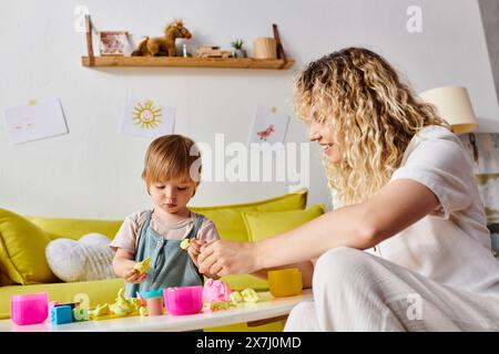 Eine lockige Mutter und ihre Kleinkind-Tochter lernen spielerisch mit der Montessori-Methode der Erziehung zu Hause. Stockfoto